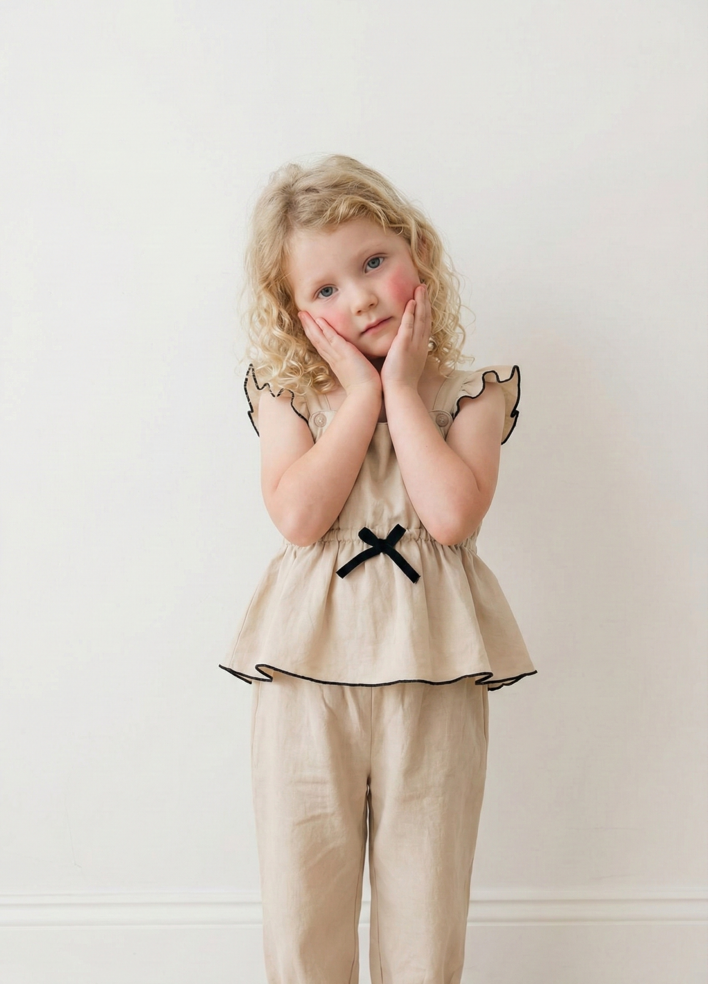 Enterito crudo con detalles negros de bengalina Jumpsuit Alice, con moño negro y volados en bota