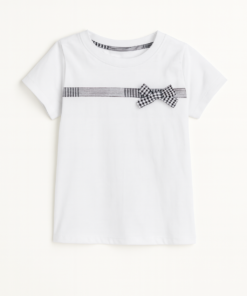Remera infantil blanca de jersey con moño cuadrillé negro y blanco en el pecho