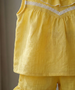 Primer plano de la tela del conjunto amarillo, mostrando la textura arrugada característica del lino coreano y el detalle de la puntilla blanca de algodón en el borde.