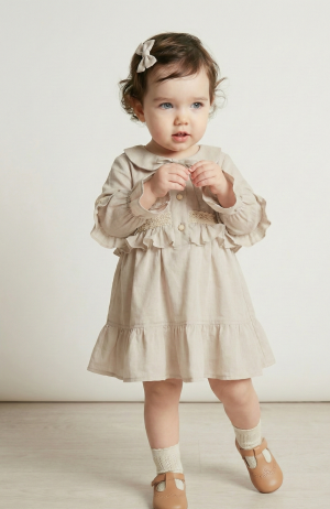 Niña pequeña usando un vestido color natural de voile de algodón con puntillas y cuello bebé. Ropa elegante estilo vintage.