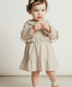 Niña pequeña usando un vestido color natural de voile de algodón con puntillas y cuello bebé. Ropa elegante estilo vintage.